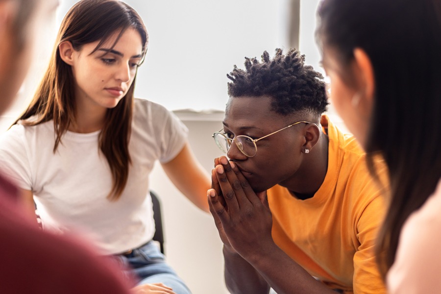 a man in orange shirt being comforted by a women