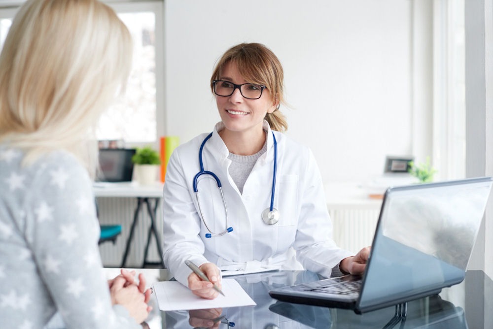 a doctor speaking to his patient while writing