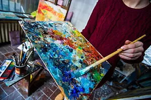 a person holding a paintbrush over a painting