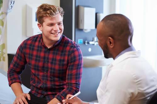 a man smiling while to talking to another man