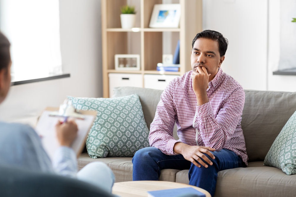 a man sitting on couch while talking to his therapist