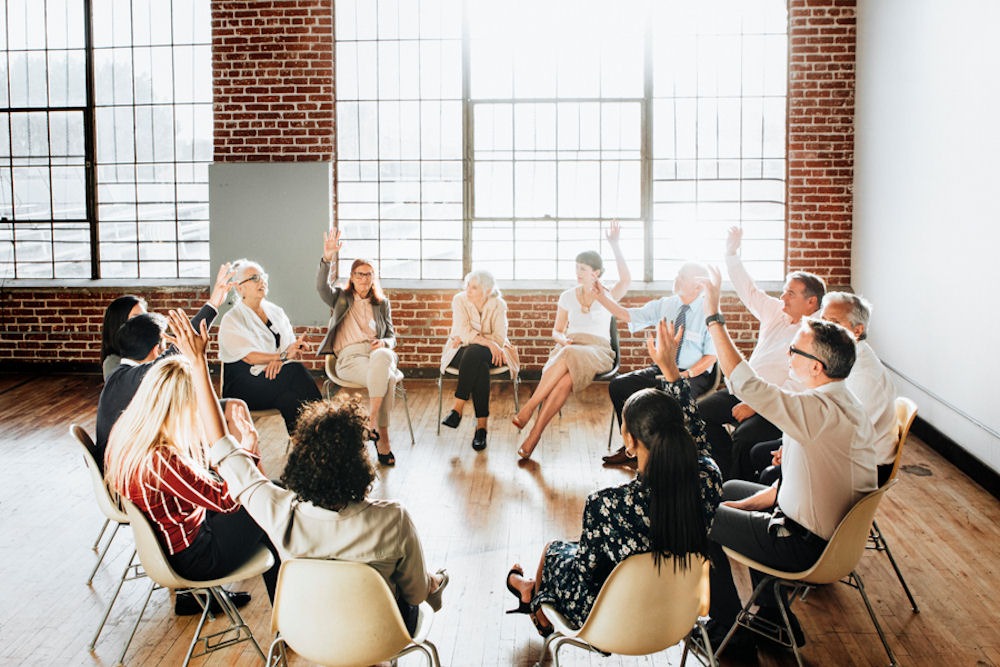 individuals raising hands in group therapy