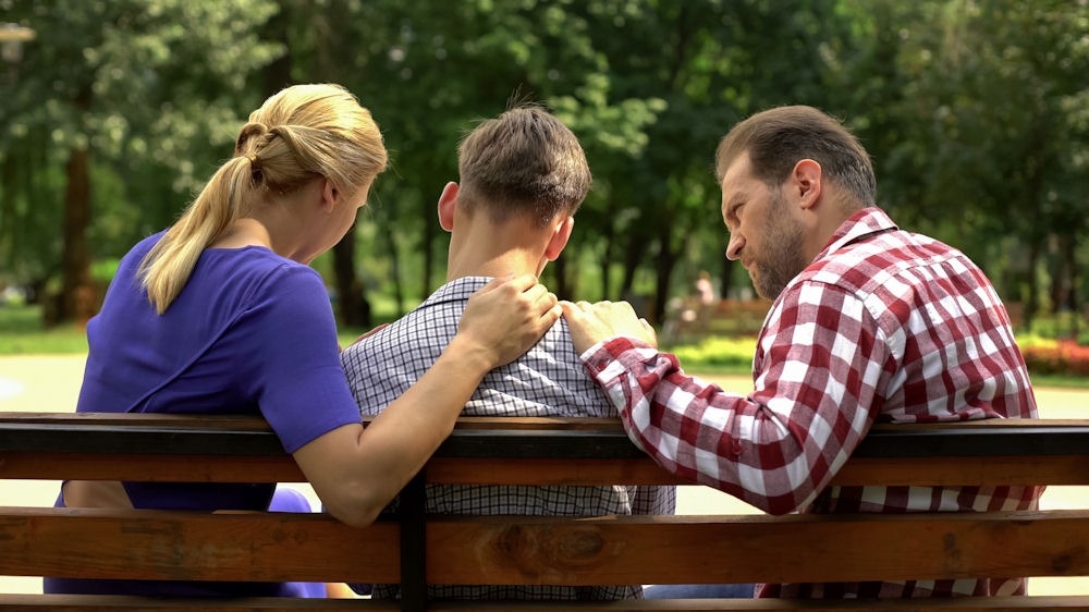 a young man being comforted by parents