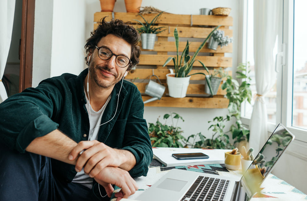 Man smiling in front of laptop promoting a positive, mental-health work culture