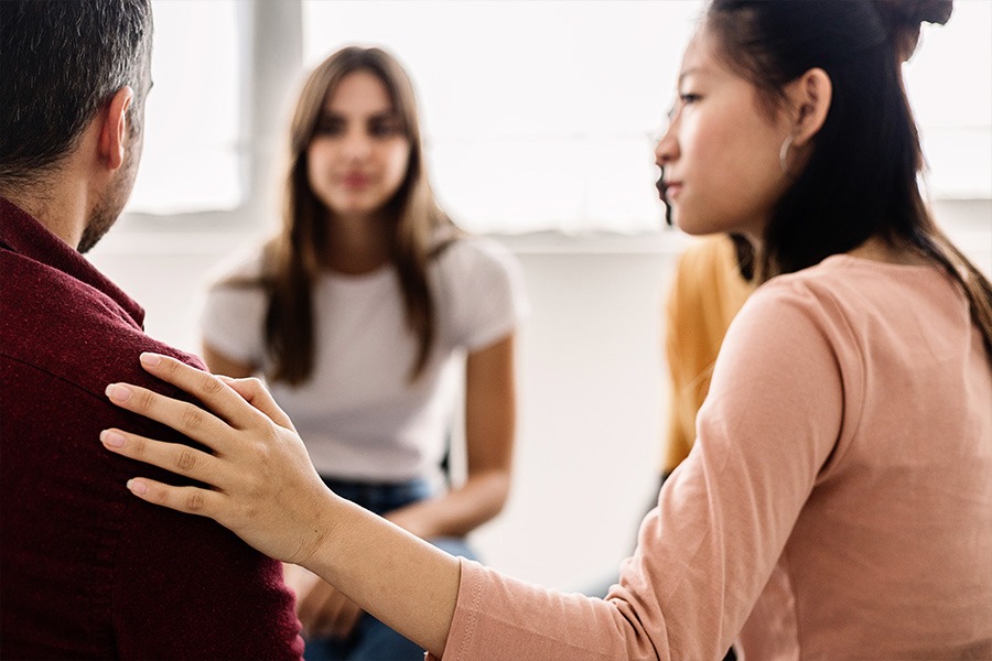 Woman comforting another individual during an AA meeting