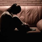 a-woman-sitting-on-couch-head-down