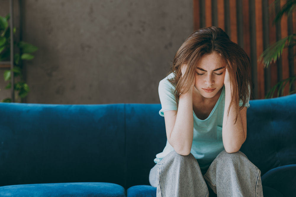Woman sitting with head in hands, showing stress, fatigue, and anxiety as visible symptoms of untreated depression.