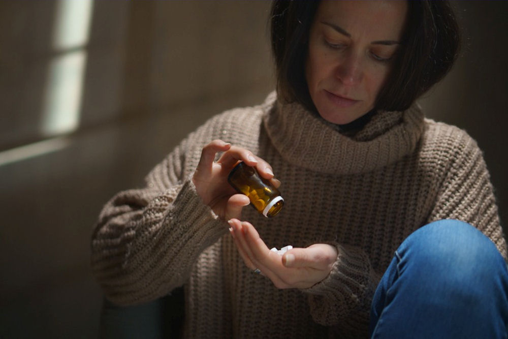 a woman pouring pills into hand